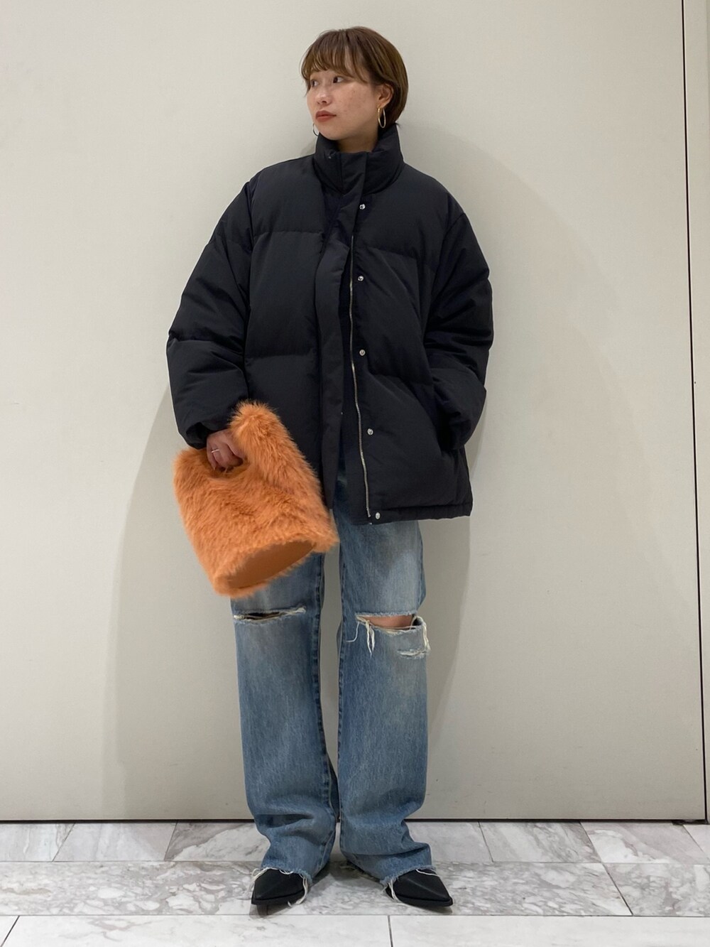 ブラック系のブーツ、オレンジ系のハンドバッグ、ブルー系のデニムパンツを着用したレディースの秋コーディネートの6枚目の写真