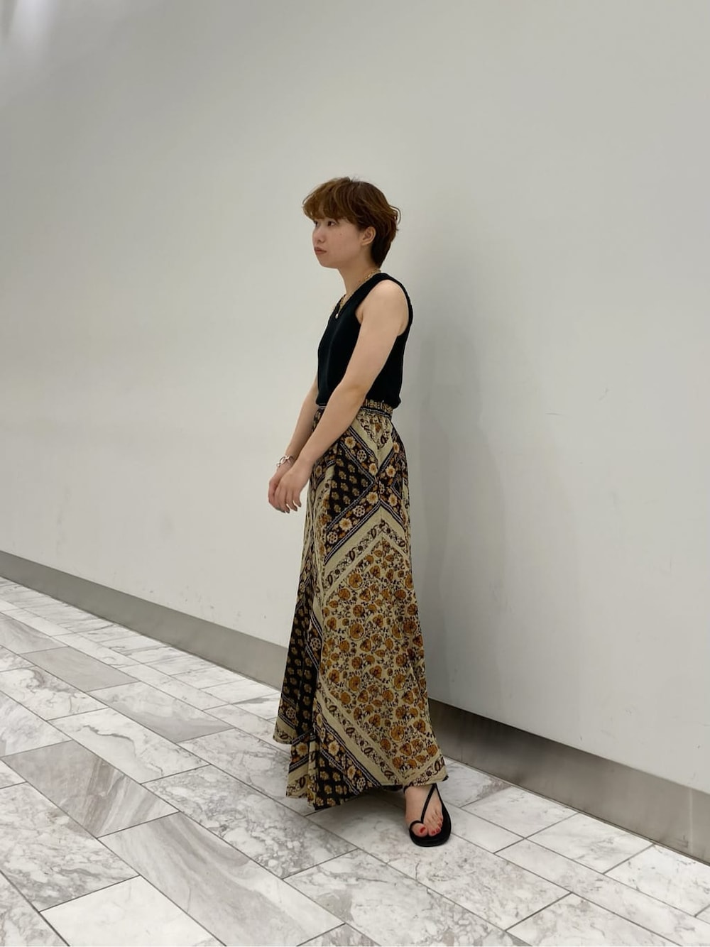 イエロー系のスカート、ブラック系のサンダル、ブラック系のタンクトップを着用したレディースの夏コーディネートの6枚目の写真