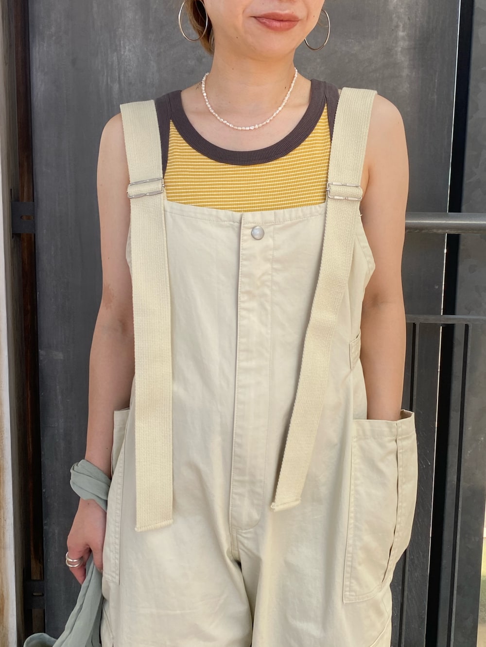 グリーン系のエコバッグ/サブバッグ、イエロー系のタンクトップ、ベージュ系のサロペット/オーバーオールを着用したレディースの夏コーディネートの4枚目の写真