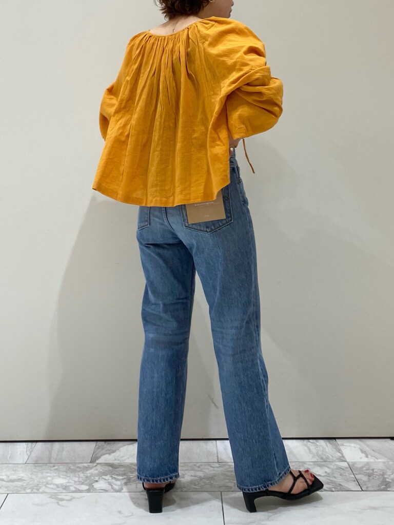 ブルー系のデニムパンツ、オレンジ系のシャツ/ブラウス、ブラック系のサンダルを着用したレディースの春コーディネートの2枚目の写真