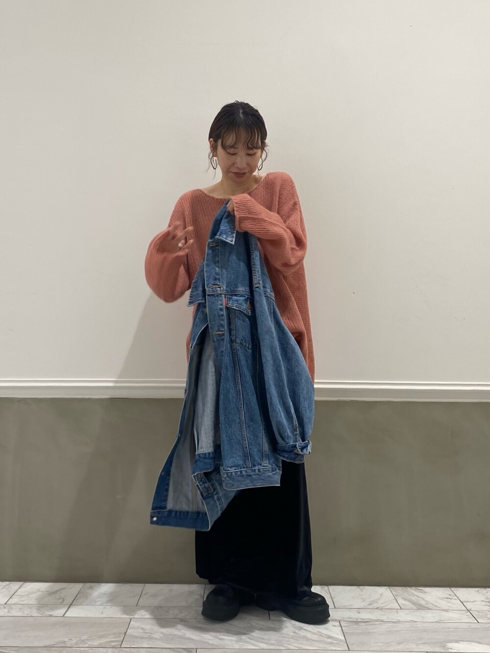 ブルー系のデニムジャケット、ピンク系のニット/セーター、ブラック系のスカートを着用したレディースの秋コーディネートの3枚目の写真