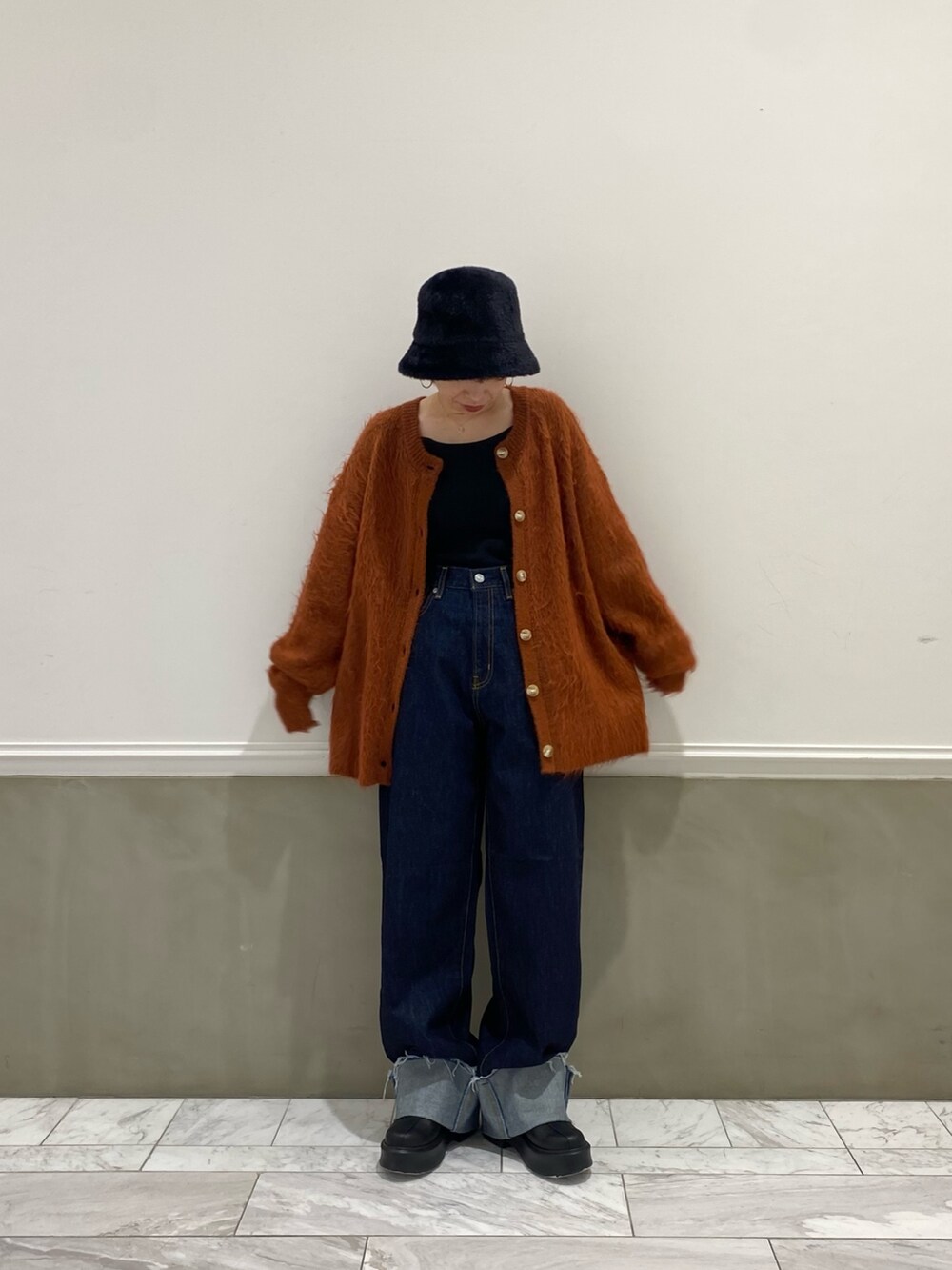 ブルー系のデニムパンツ、オレンジ系のカーディガン/ボレロ、ブラック系のハットを着用したレディースの秋コーディネートの2枚目の写真