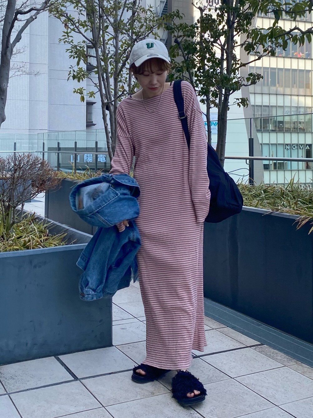 ピンク系のワンピース、ブルー系のデニムジャケット、ブラック系のバックパック/リュックを着用したレディースの冬コーディネートの3枚目の写真