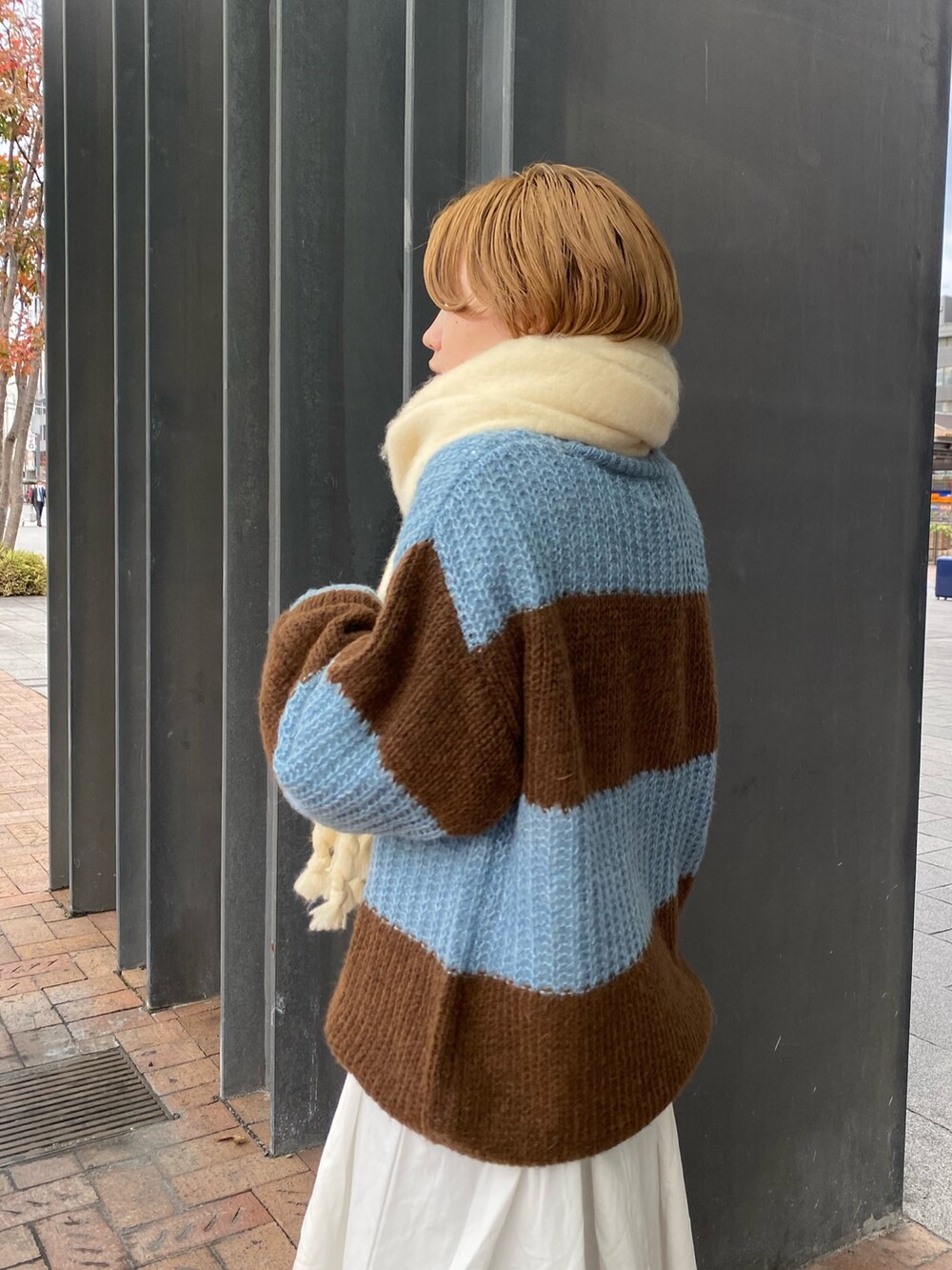 ブルー系のニット/セーター、ブラック系のワンピース、ホワイト系のマフラーを着用したレディースの秋コーディネートの4枚目の写真