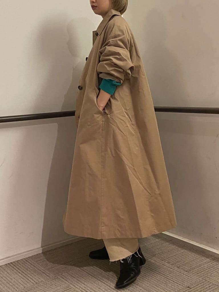 ベージュ系のステンカラーコート、グリーン系のスウェット、ホワイト系のデニムパンツを着用したレディースの冬コーディネートの5枚目の写真