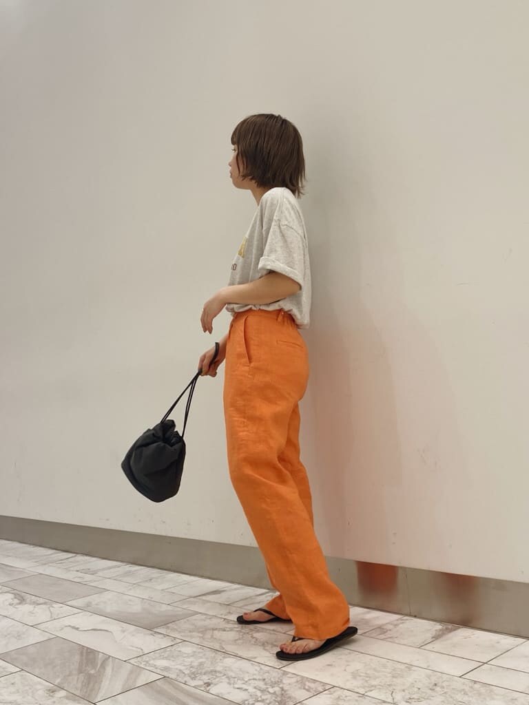 グレー系のハンドバッグ、グレー系のTシャツ/カットソー、オレンジ系のその他パンツを着用したレディースの春コーディネートの2枚目の写真