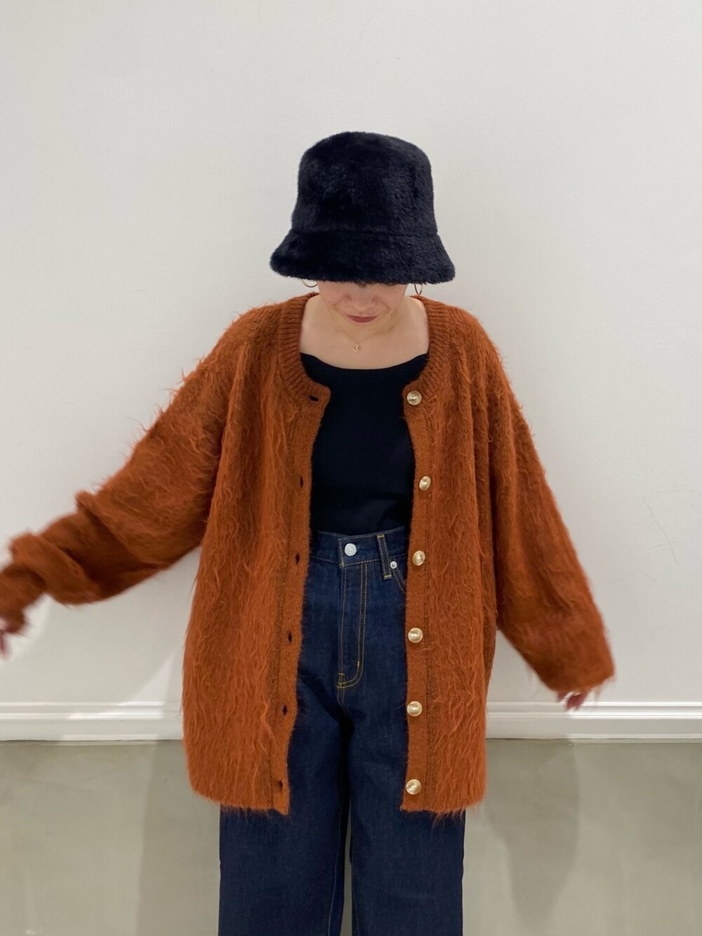 ブルー系のデニムパンツ、オレンジ系のカーディガン/ボレロ、ブラック系のハットを着用したレディースの秋コーディネートの3枚目の写真