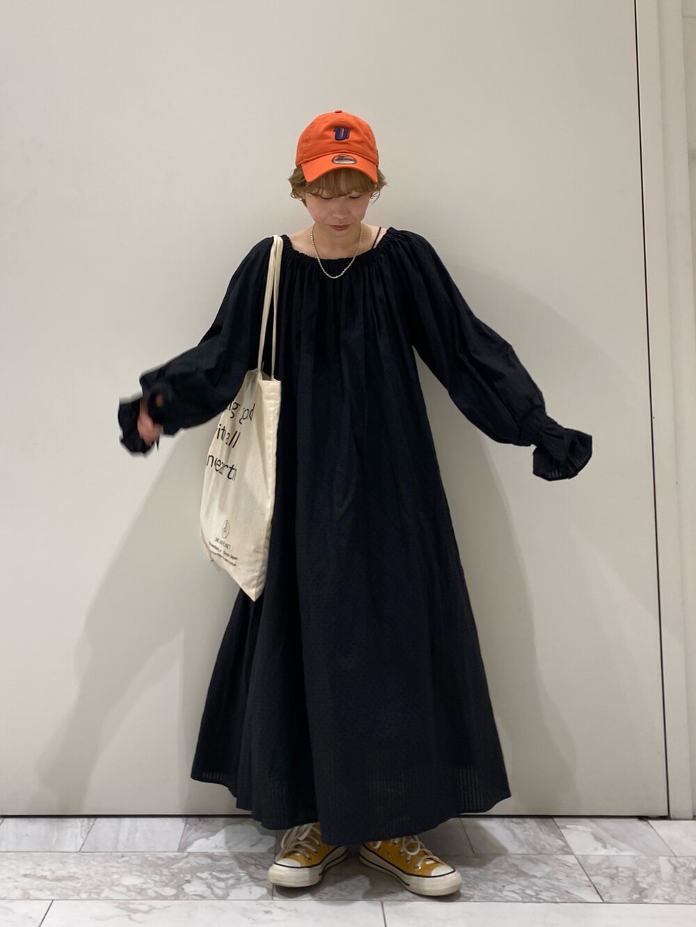 ブラック系のワンピース、オレンジ系のキャップを着用したレディースの春コーディネートの3枚目の写真