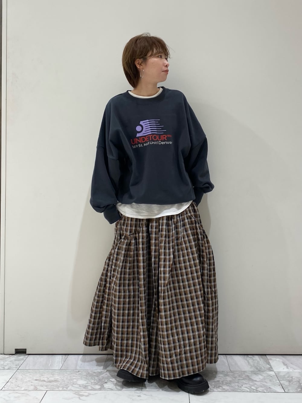 グレー系のスウェット、ブラウン系のスカート、ホワイト系のTシャツ/カットソーを着用したレディースの冬コーディネートの2枚目の写真