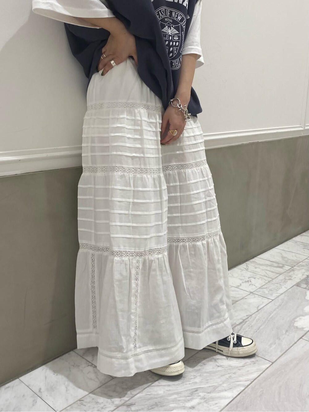 ホワイト系のスカート、ブラウン系のブーツ、ブラウン系のトレンチコートを着用したレディースの夏コーディネートの4枚目の写真