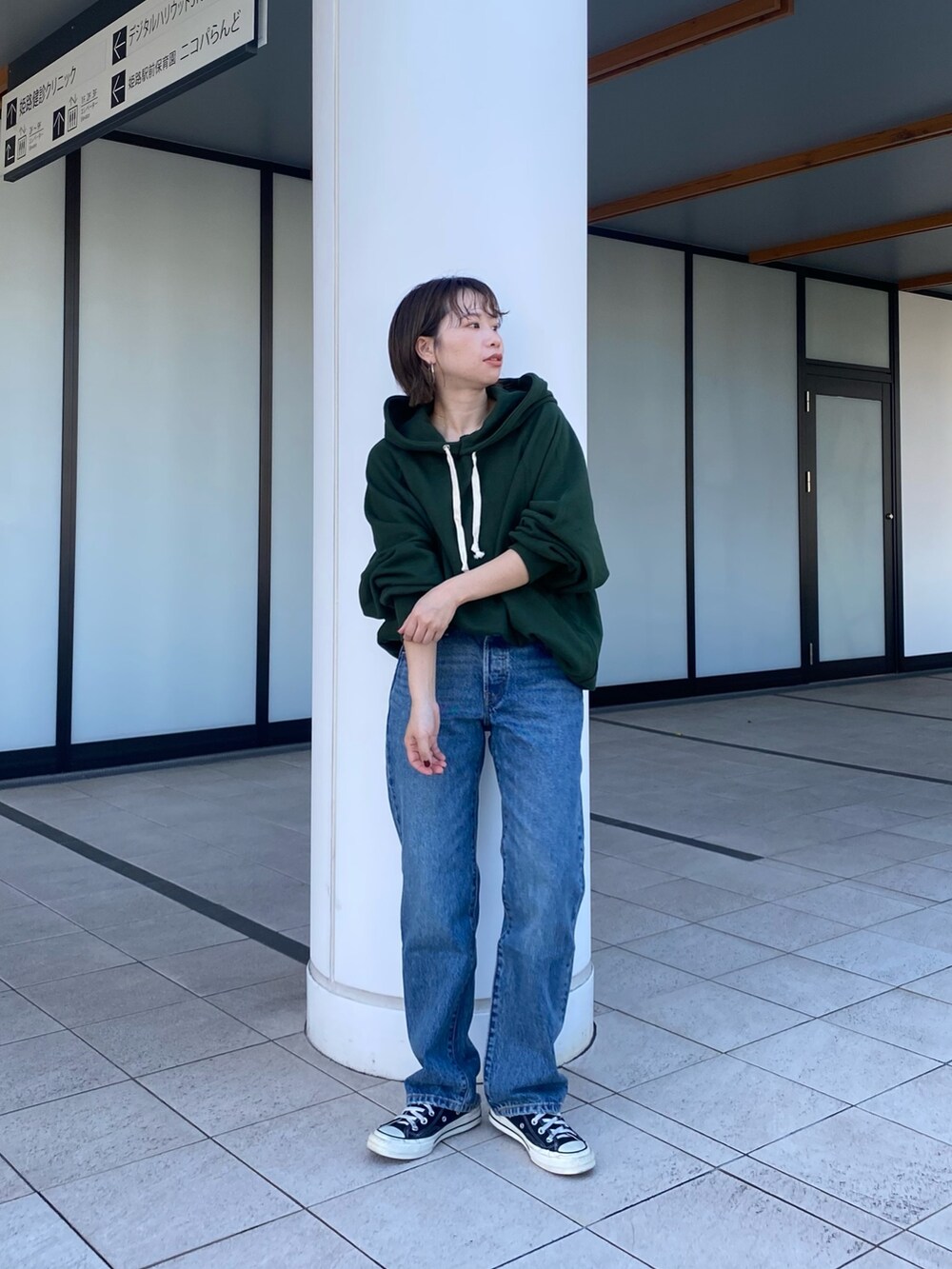 グリーン系のパーカー、ブルー系のデニムパンツを着用したレディースの秋コーディネートの3枚目の写真