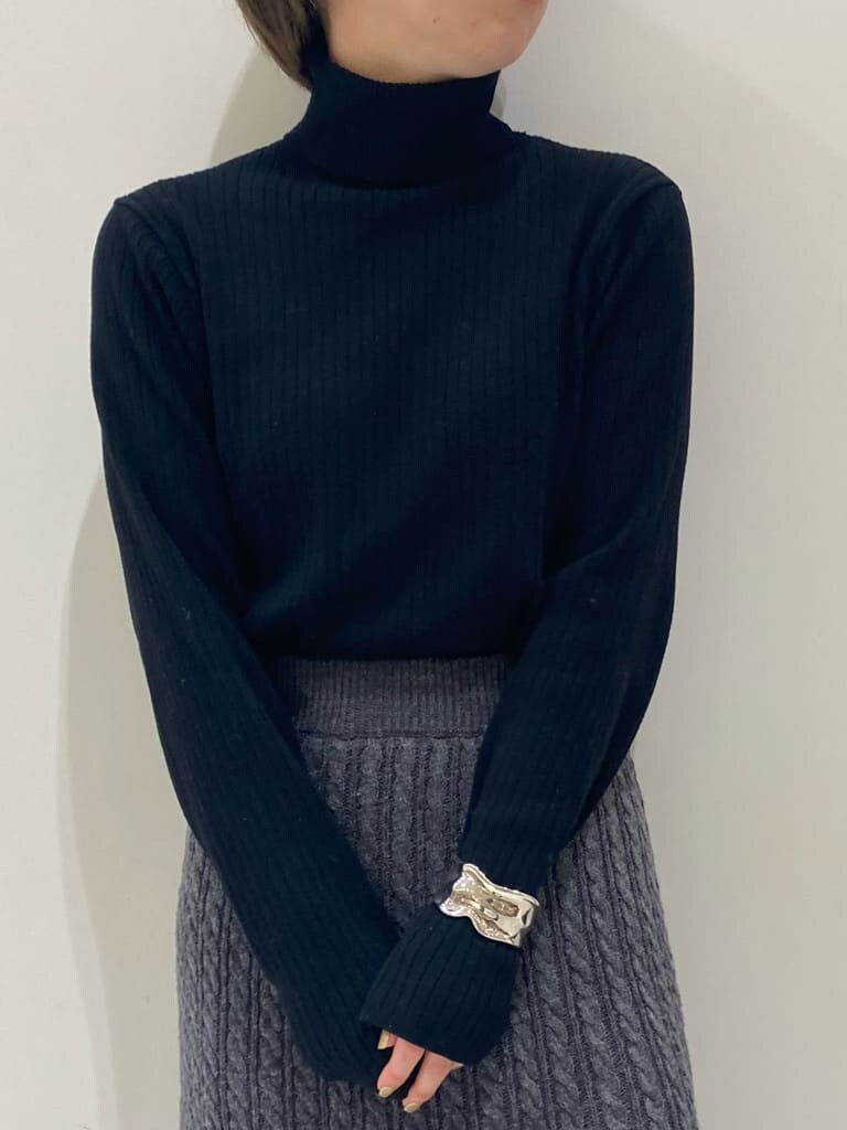 グレー系のスカート、ホワイト系のダウンジャケット/コート、ブラック系のニット/セーターを着用したレディースの秋コーディネートの4枚目の写真