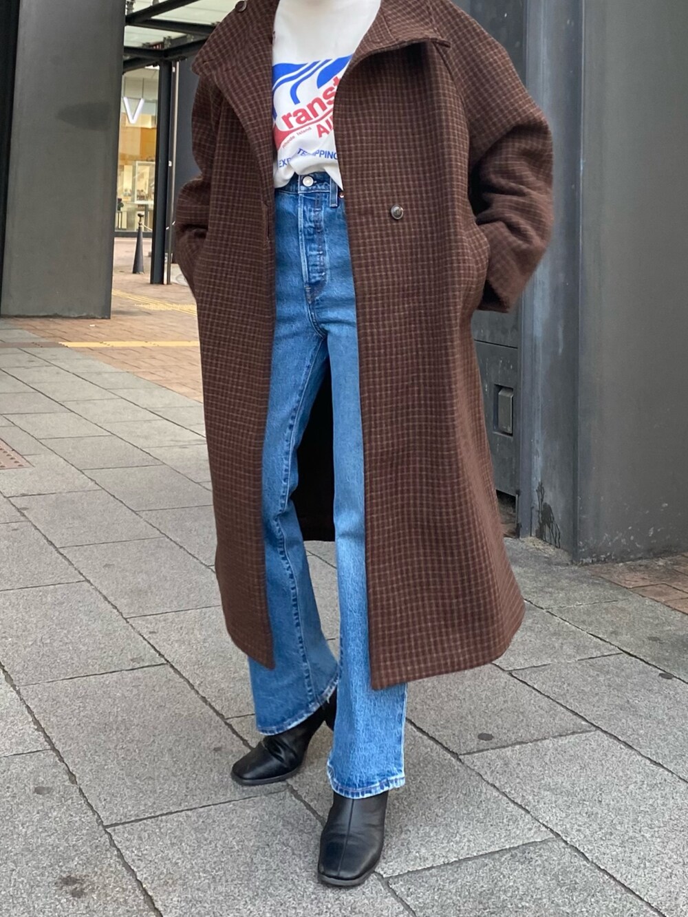 ホワイト系のスウェット、ブラウン系のその他アウター、ブルー系のデニムパンツを着用したレディースの冬コーディネートの4枚目の写真