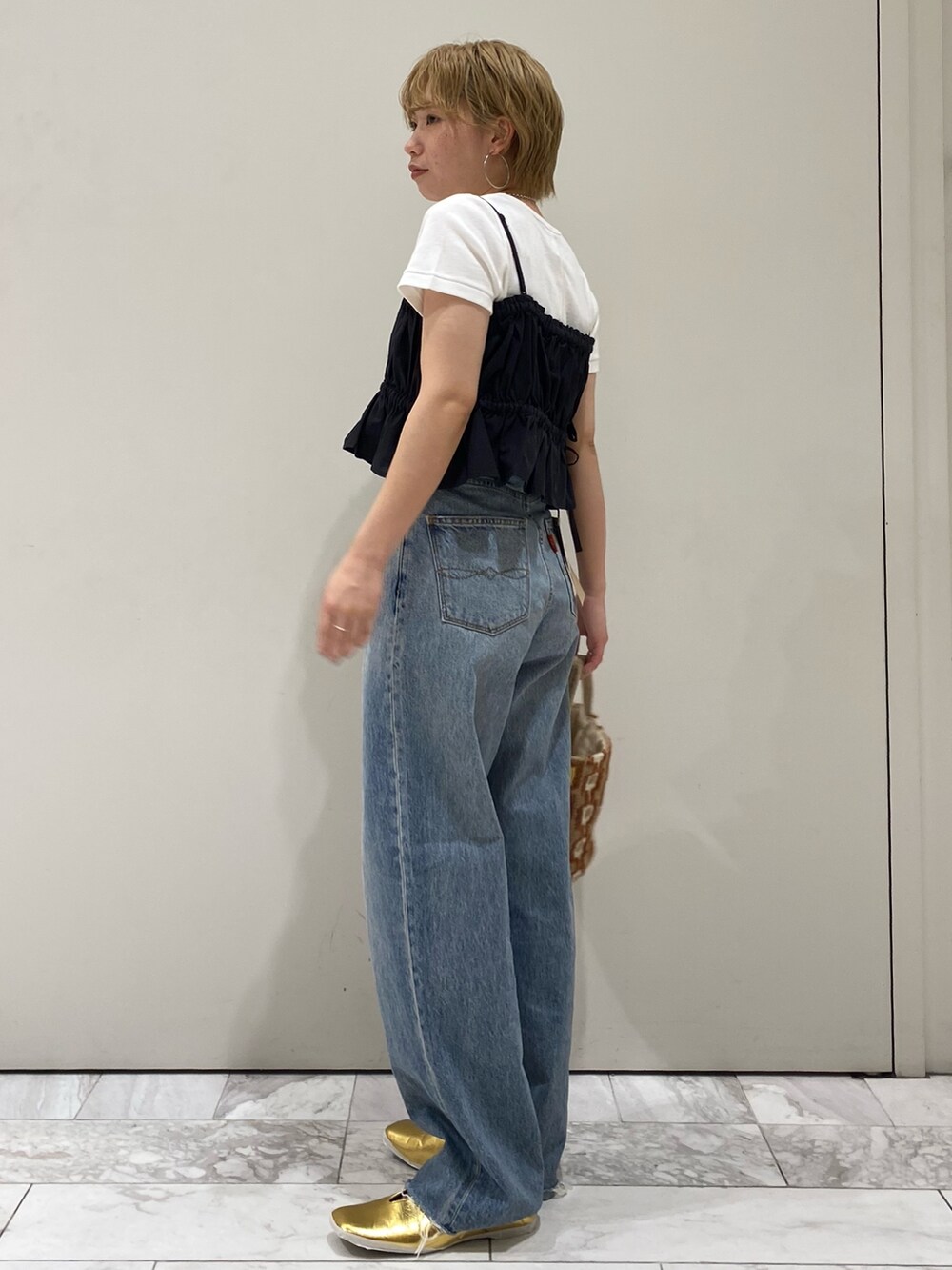 ブラック系のワンピース、ホワイト系のTシャツ/カットソー、ゴールド系のパンプスを着用したレディースの春コーディネートの2枚目の写真
