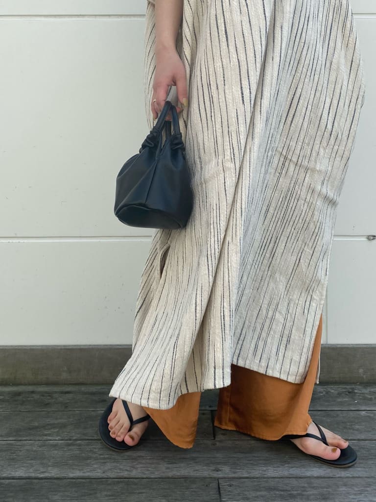 オレンジ系のその他パンツ、オレンジ系のワンピース、ブラック系のハンドバッグを着用したレディースの春コーディネートの3枚目の写真