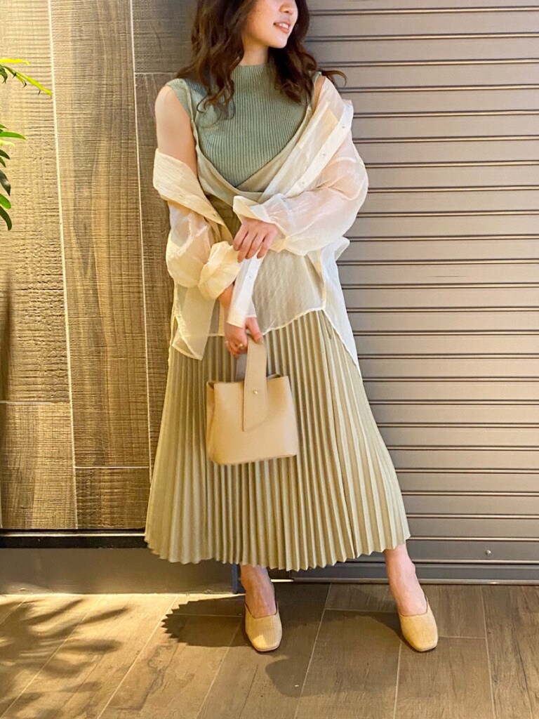 ベージュ系のワンピース、グリーン系のニット/セーター、ホワイト系のハンドバッグを着用したレディースの春コーディネートの3枚目の写真