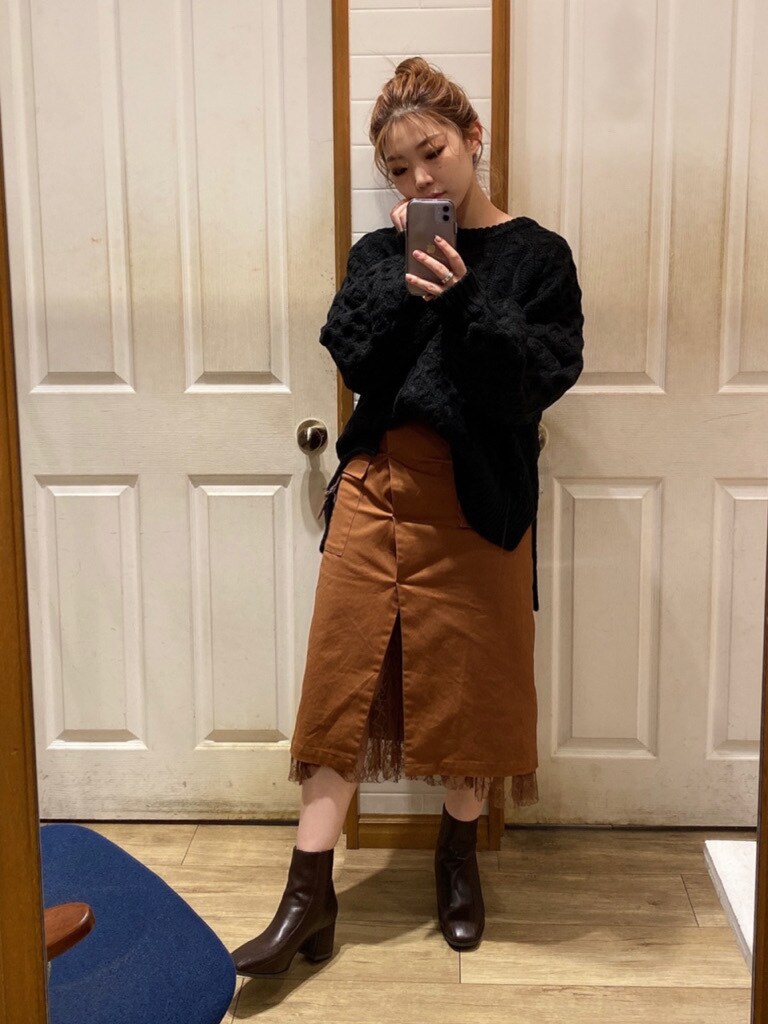 ブラウン系のスカート、ブラウン系のブーツ、ブラック系のニット/セーターを着用したレディースの秋コーディネートの4枚目の写真