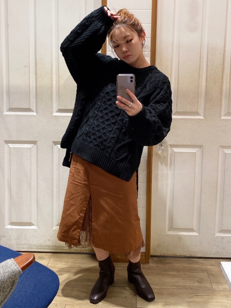 ブラウン系のスカート、ブラウン系のブーツ、ブラック系のニット/セーターを着用したレディースの秋コーディネートの2枚目の写真