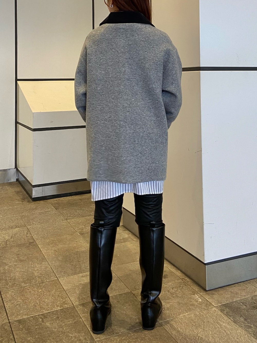 グレー系のブルゾン、ブラック系のブーツ、グレー系のニット/セーターを着用したレディースの秋コーディネートの3枚目の写真