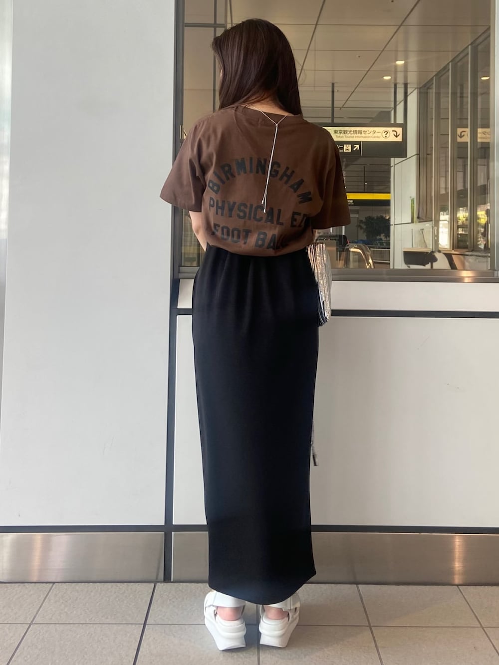 ブラック系のスカート、ブラウン系のTシャツ/カットソー、ホワイト系のサンダルを着用したレディースの春コーディネートの3枚目の写真