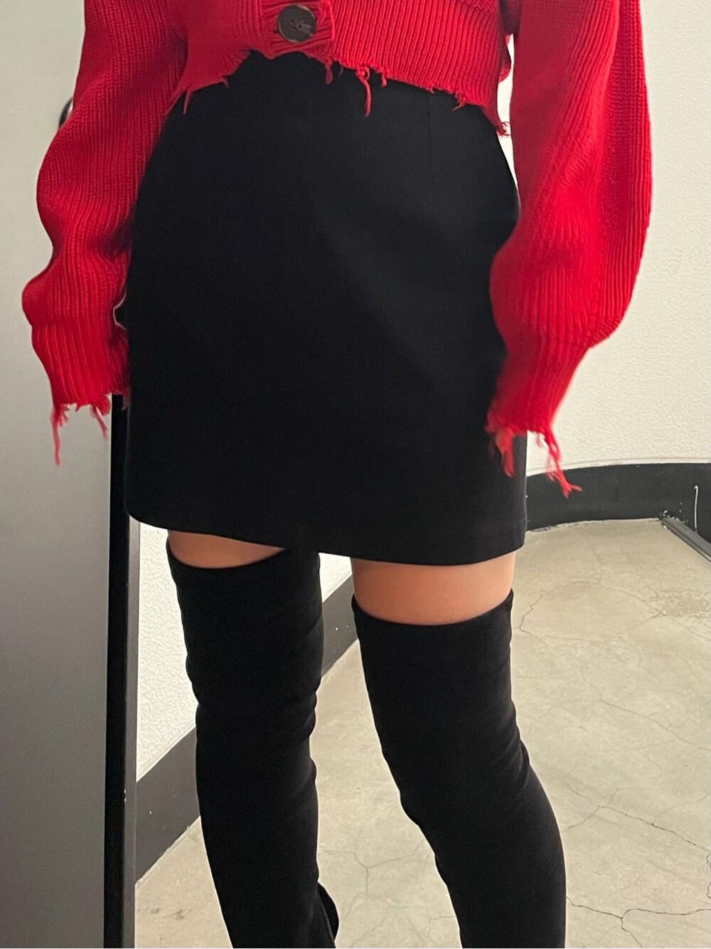 ブラック系のスカート、レッド系のカーディガン/ボレロ、ブラック系のブーツを着用したレディースの秋コーディネートの6枚目の写真