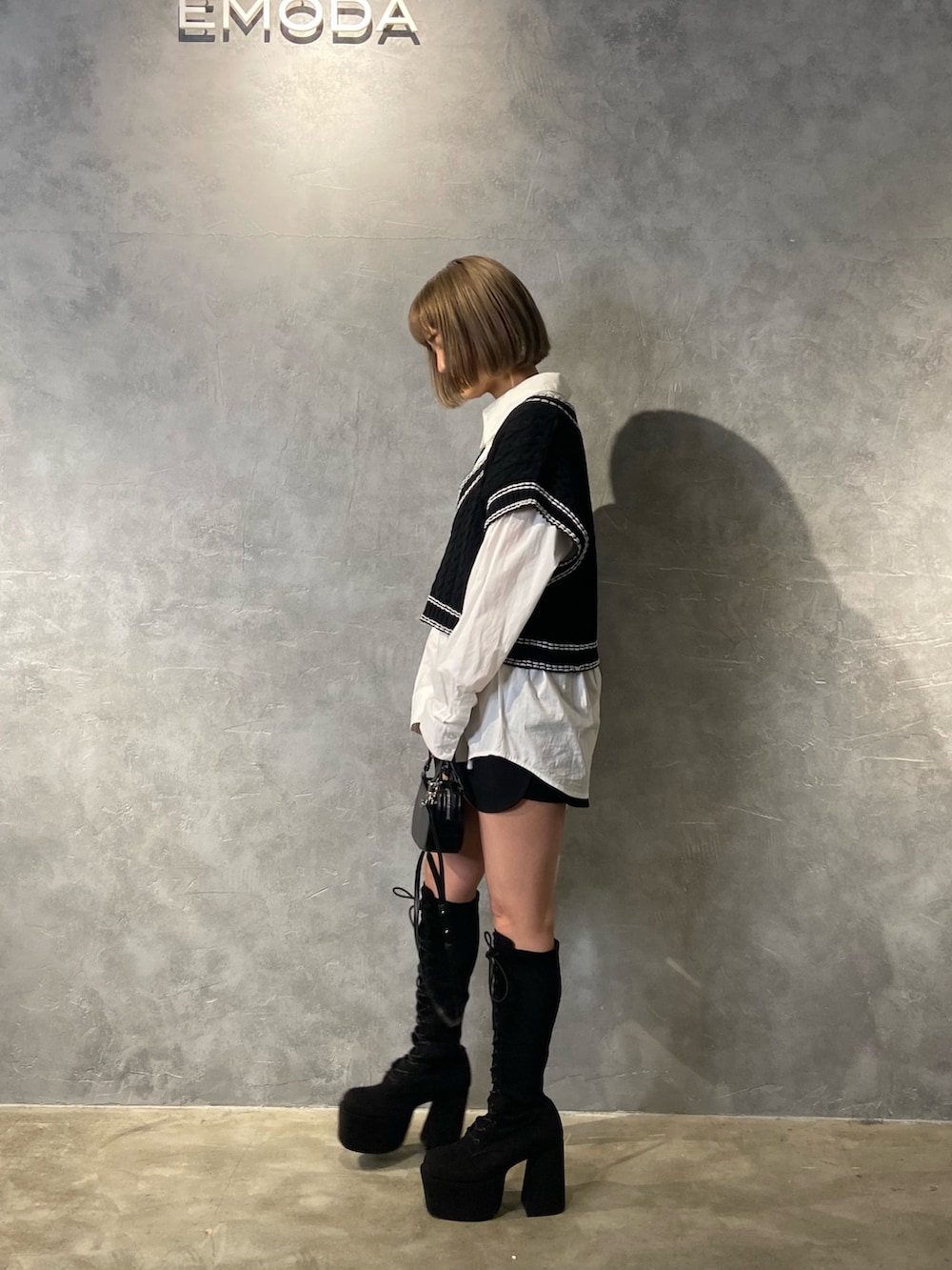 ブラック系のベスト、ホワイト系のシャツ/ブラウス、ブラック系のブーツを着用したレディースの冬コーディネートの3枚目の写真