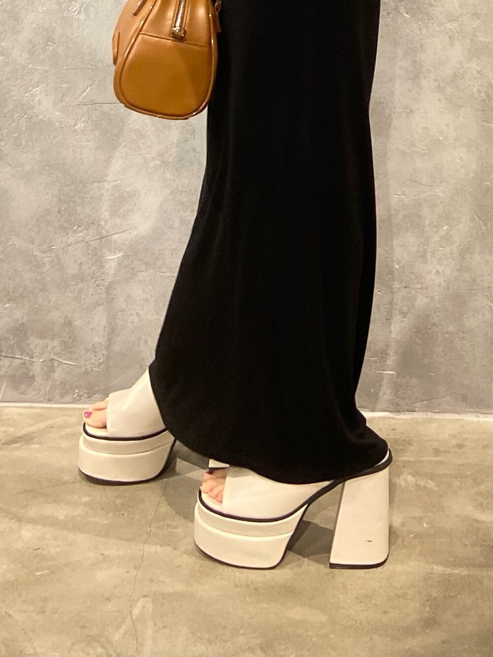 ブラック系のワンピース、ブラック系のハンドバッグ、ホワイト系のサンダルを着用したレディースの春コーディネートの7枚目の写真