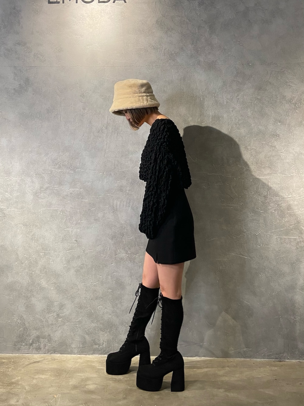 ブラック系のTシャツ/カットソー、ブラック系のスカート、ブラック系のブーツを着用したレディースの冬コーディネートの3枚目の写真