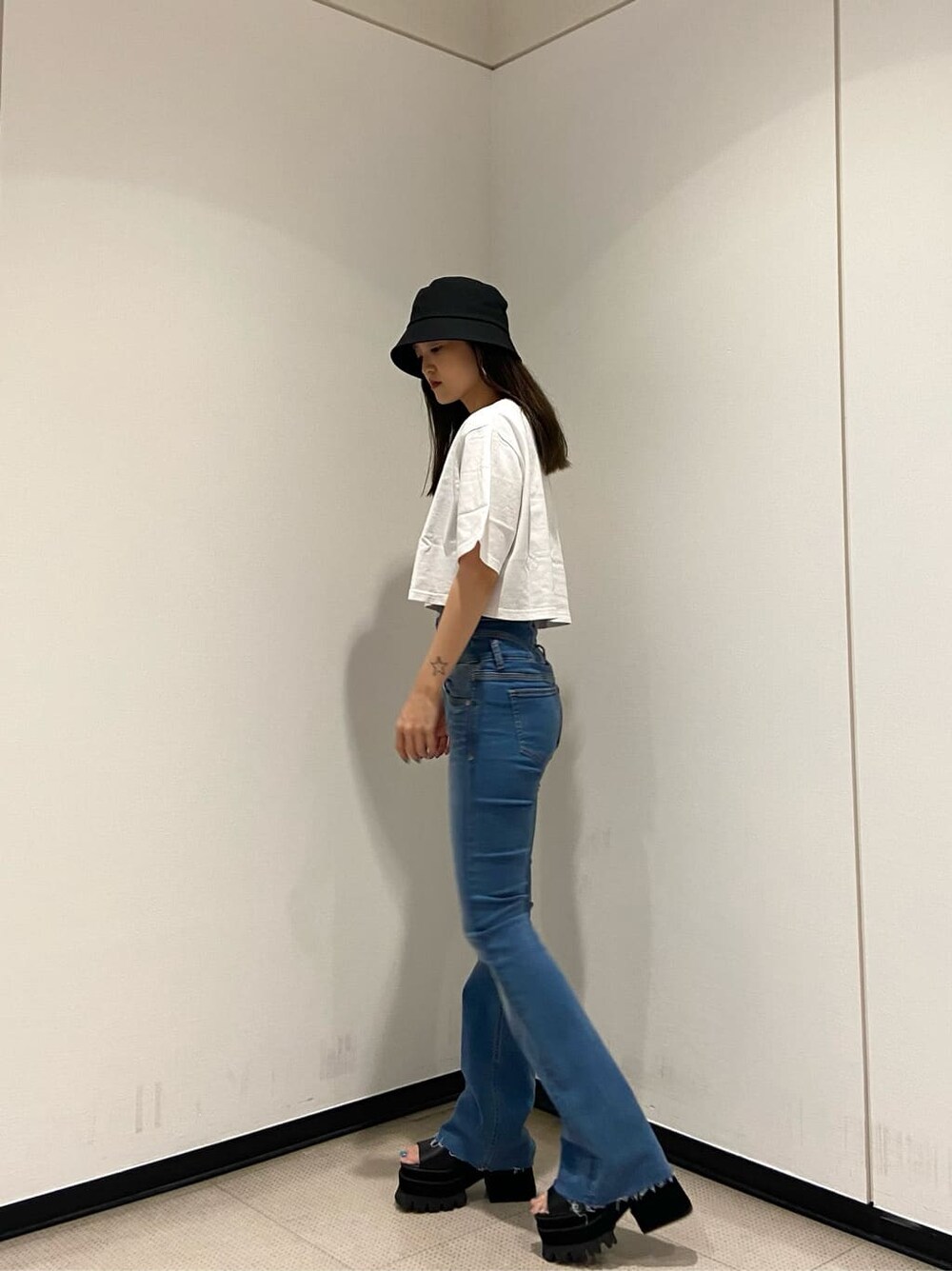 ブルー系のデニムパンツ、ブラック系のサンダル、ホワイト系のTシャツ/カットソーを着用したレディースの夏コーディネートの3枚目の写真