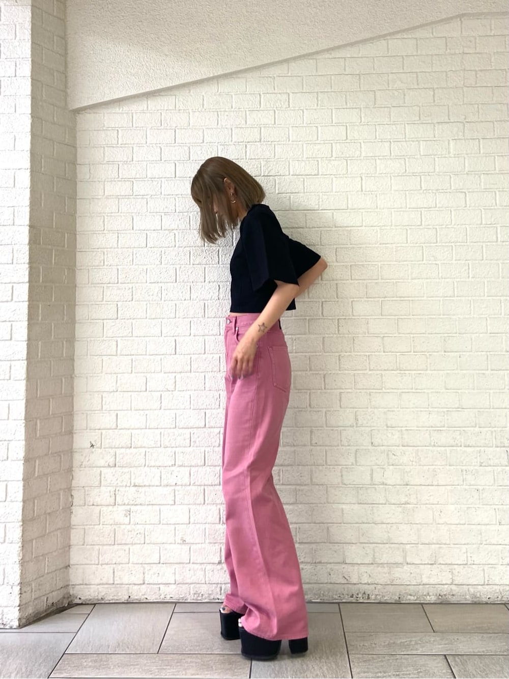 ピンク系のデニムパンツ、ブラック系のサンダル、ブラック系のTシャツ/カットソーを着用したレディースの夏コーディネートの3枚目の写真