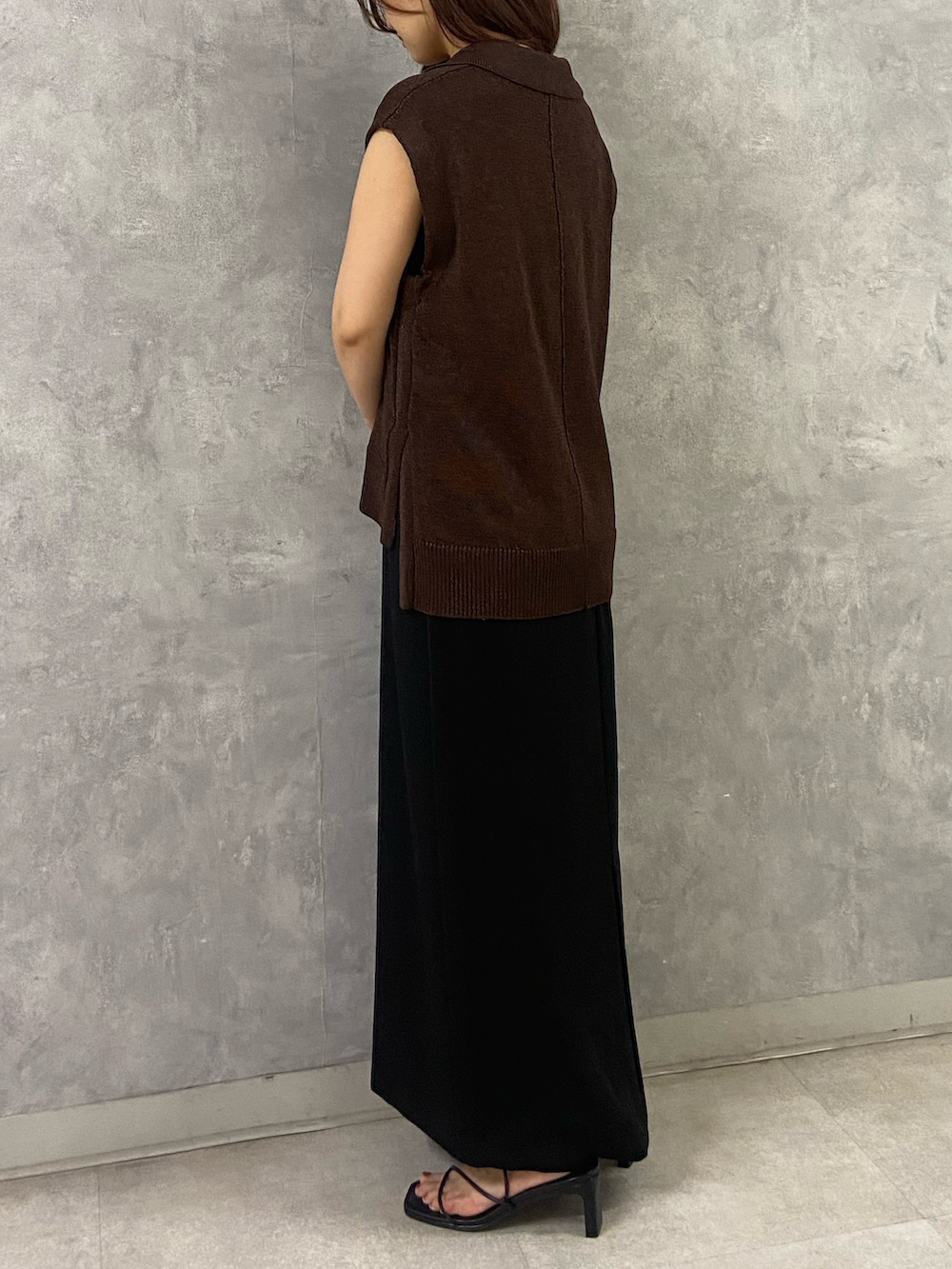 ブラウン系のベスト、ブラック系のワンピース、ブラック系のサンダルを着用したレディースの夏コーディネートの2枚目の写真