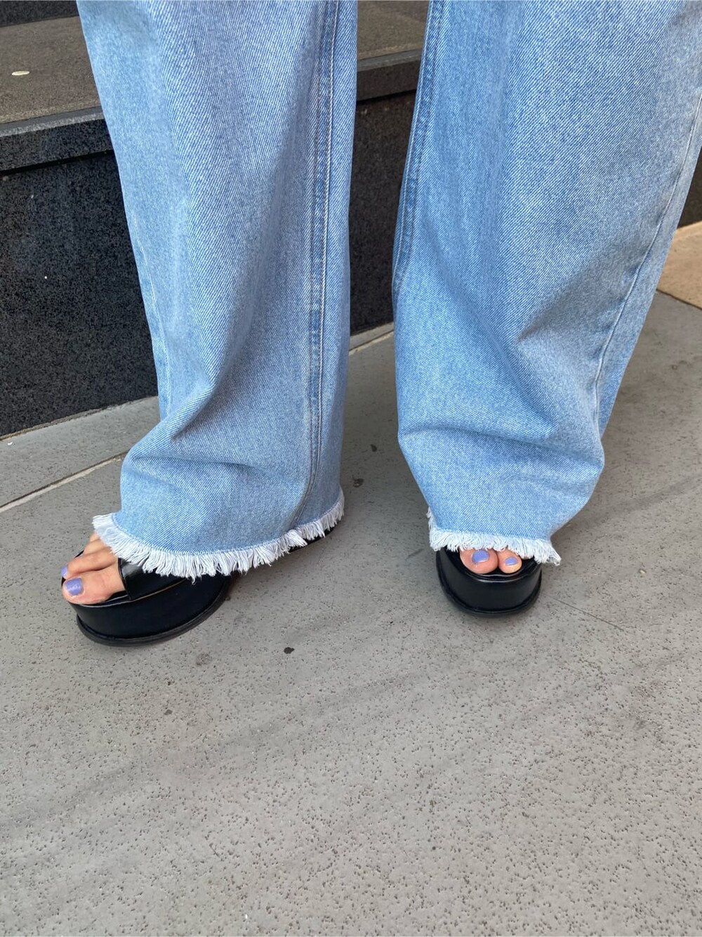 ブラック系のサンダル、ブルー系のデニムパンツ、ブラック系のTシャツ/カットソーを着用したレディースの春コーディネートの7枚目の写真