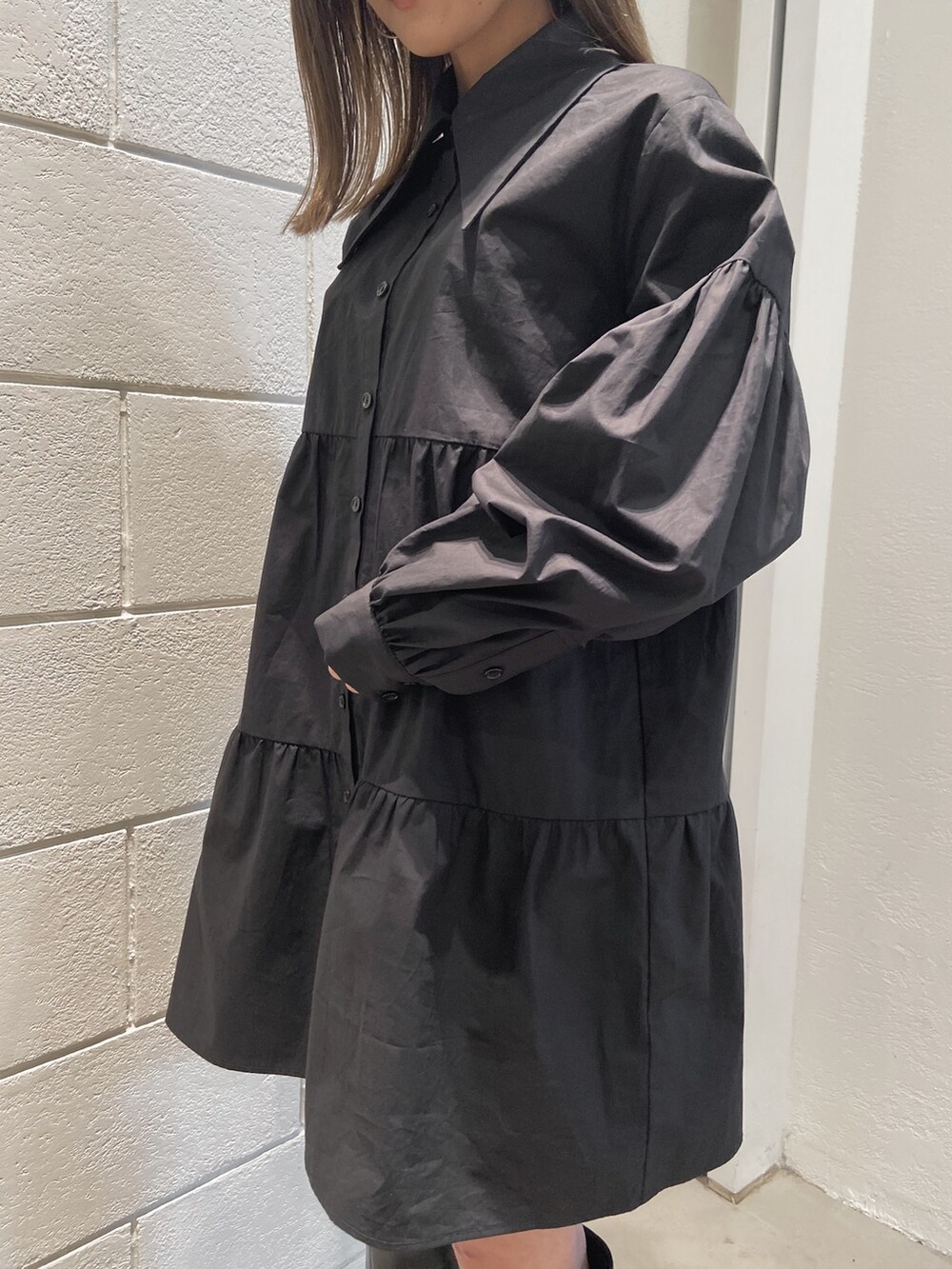 ブラック系のシャツワンピース、ブラック系のブーツ、ブラック系のハンドバッグを着用したレディースの冬コーディネートの4枚目の写真