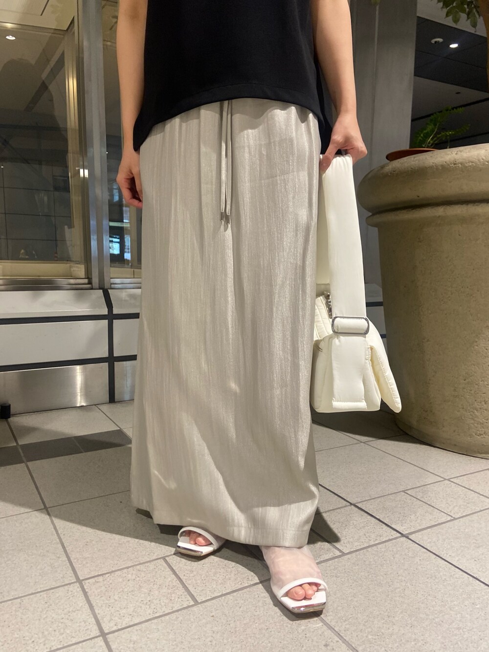 ブラック系のTシャツ/カットソー、ベージュ系のスカート、ホワイト系のサンダルを着用したレディースの春コーディネートの6枚目の写真