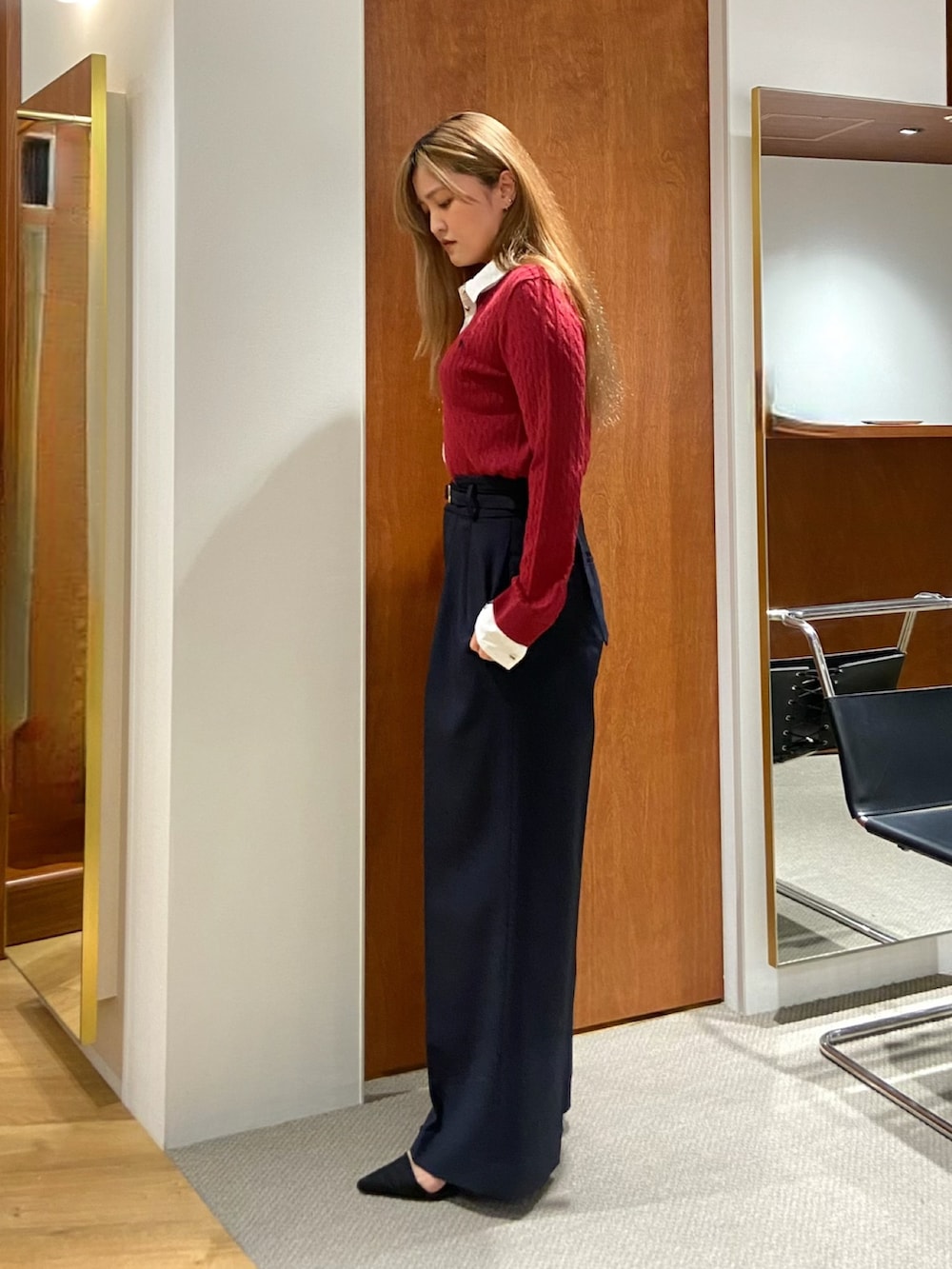 レッド系のニット/セーター、ブルー系のスラックスを着用したレディースの秋コーディネートの2枚目の写真