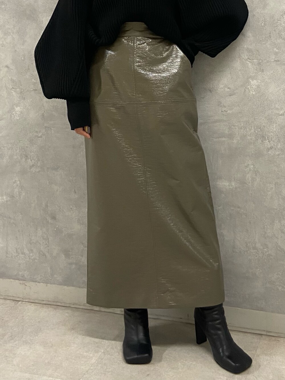 ブラック系のニット/セーター、グリーン系のスカート、ブラック系のブーツを着用したレディースの秋コーディネートの5枚目の写真