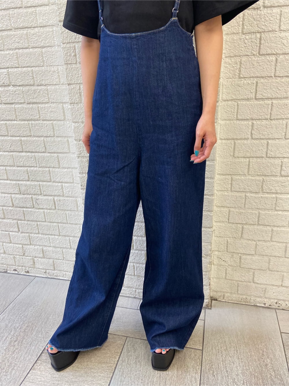 ブラック系のサンダル、ブルー系のサロペット/オーバーオール、ブラック系のTシャツ/カットソーを着用したレディースの夏コーディネートの6枚目の写真