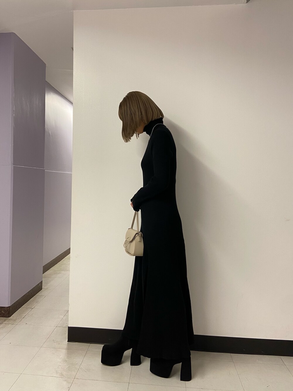 ブラック系のワンピース、ホワイト系のショルダーバッグ、ブラック系のブーツを着用したレディースの秋コーディネートの3枚目の写真