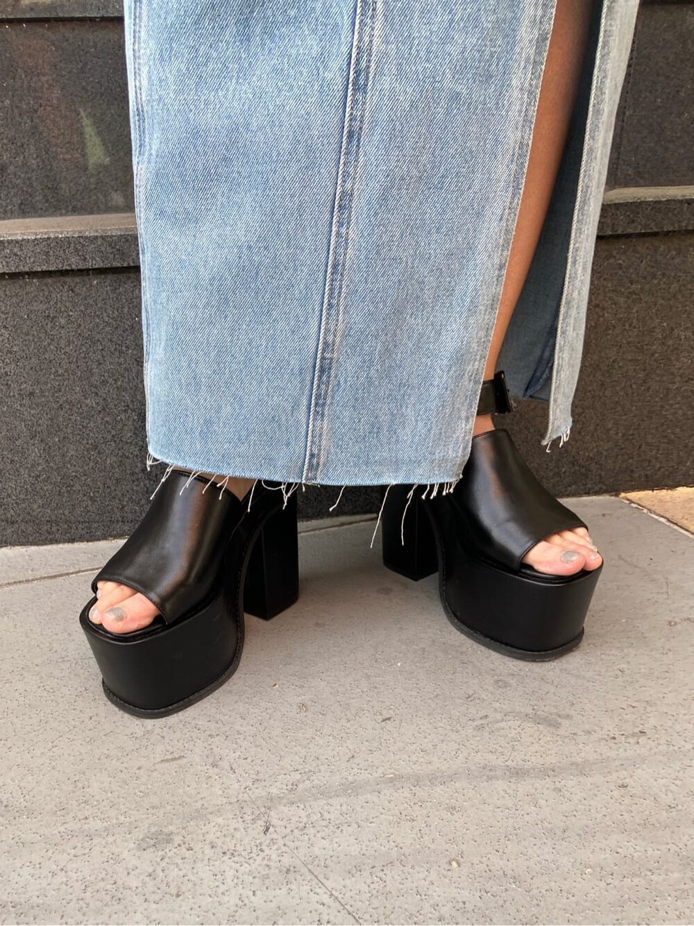 ブルー系のスカート、ブラック系のTシャツ/カットソー、ブラック系のサンダルを着用したレディースの春コーディネートの7枚目の写真