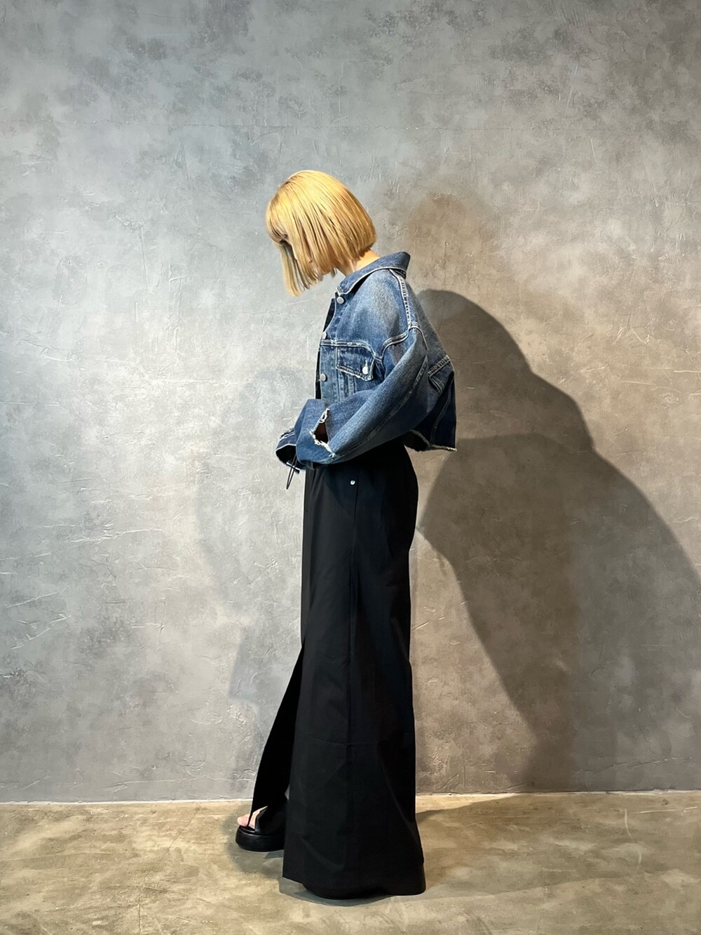 ブルー系のデニムジャケット、ベージュ系のキャミソール、ブラック系のスカートを着用したレディースの春コーディネートの2枚目の写真