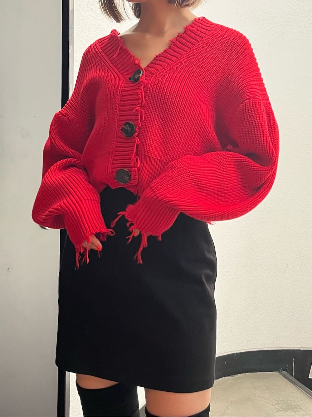 ブラック系のスカート、レッド系のカーディガン/ボレロ、ブラック系のブーツを着用したレディースの秋コーディネートの5枚目の写真