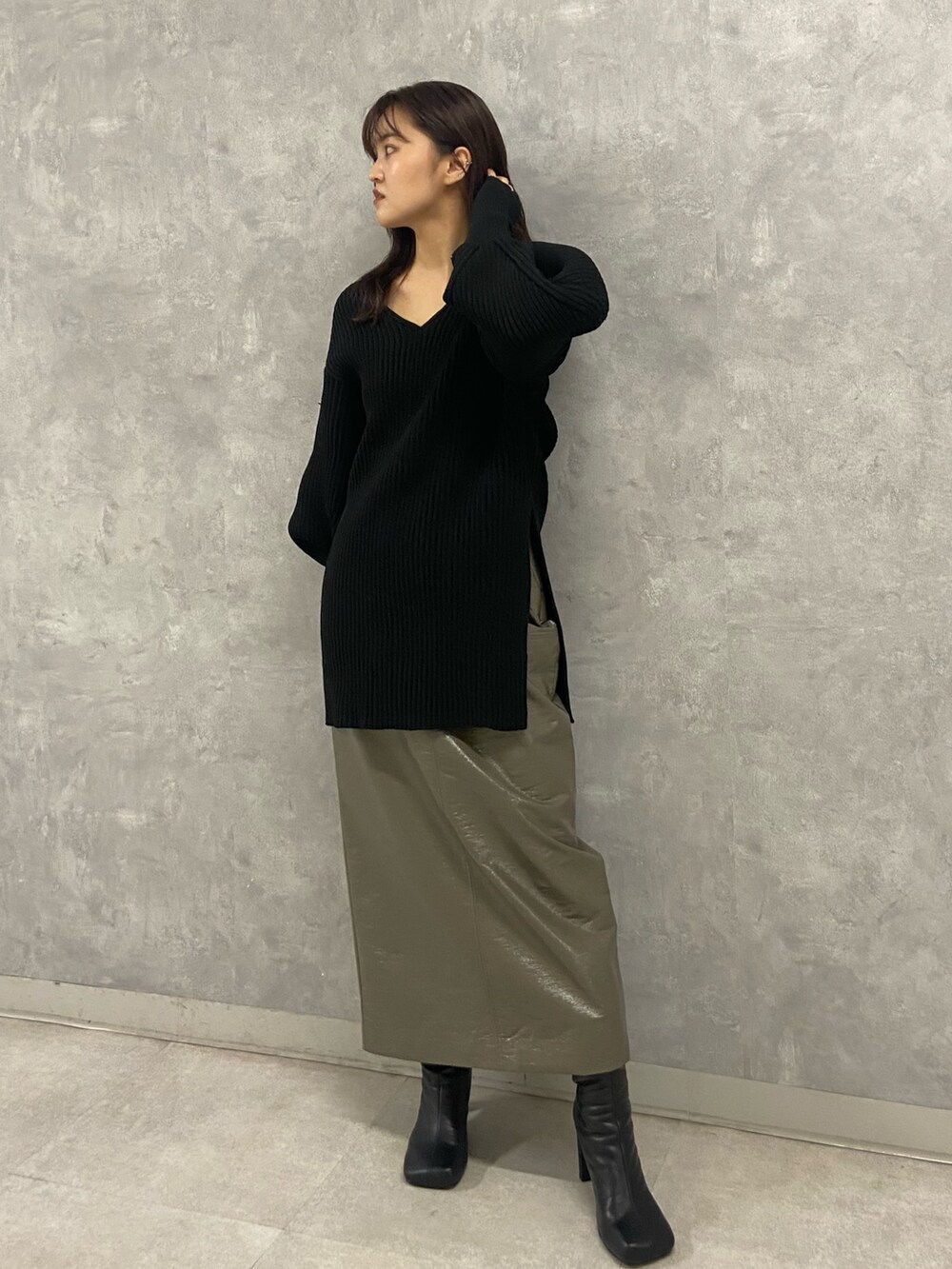 ブラック系のニット/セーター、グリーン系のスカート、ブラック系のブーツを着用したレディースの秋コーディネートの2枚目の写真