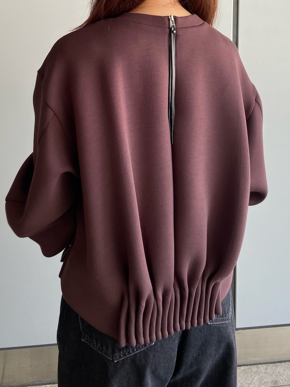 ブラウン系のスウェット、ブラック系のデニムパンツ、ブラック系のローファーを着用したレディースの夏コーディネートの6枚目の写真