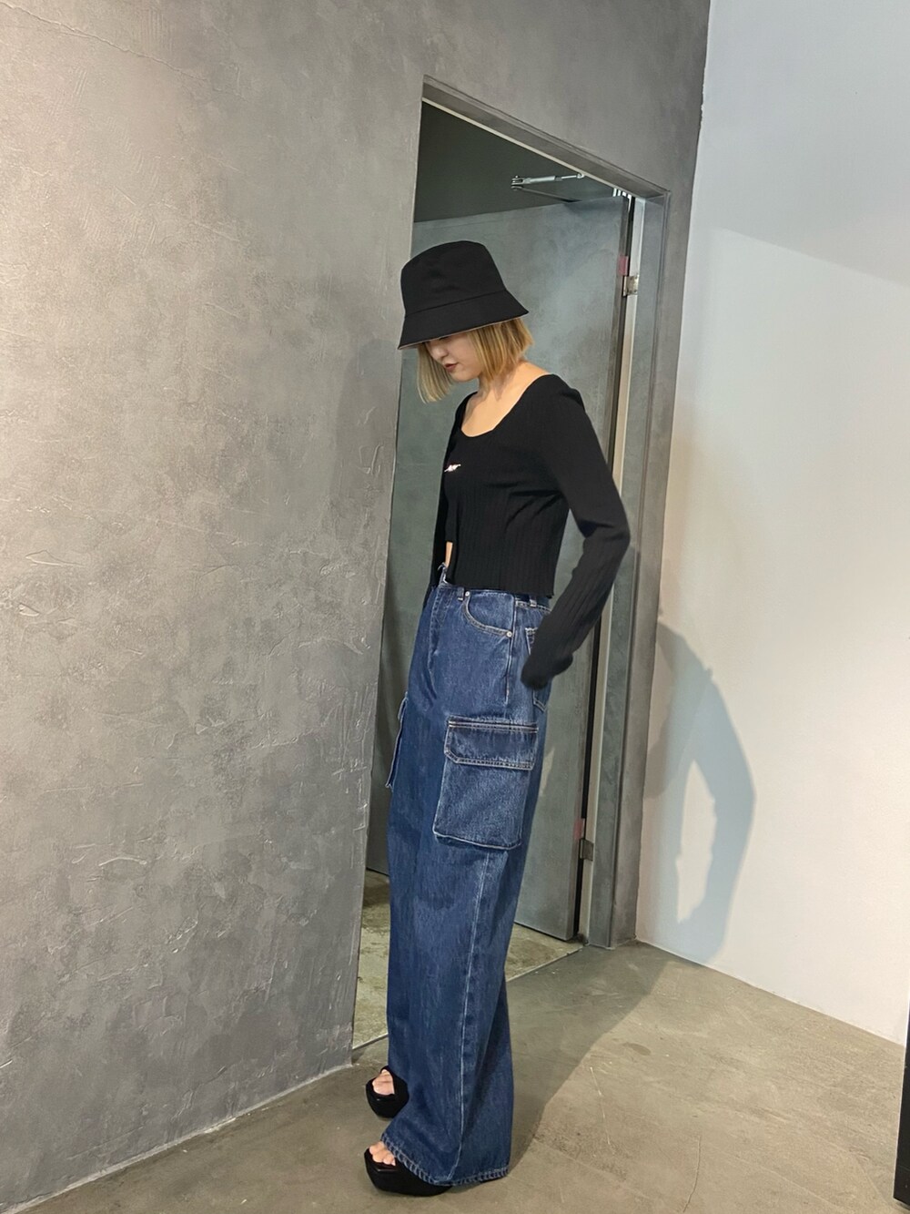 ブラック系のTシャツ/カットソー、ブルー系のデニムパンツ、ブラック系のサンダルを着用したレディースの冬コーディネートの2枚目の写真