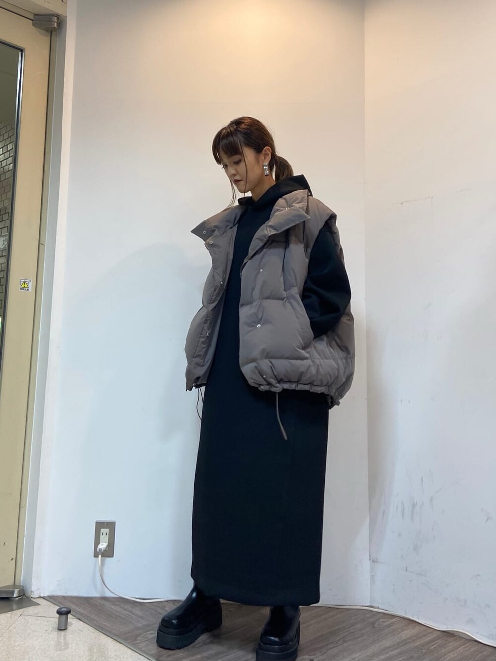 グレー系のダウンベスト、ブラック系のワンピースを着用したレディースの秋コーディネートの7枚目の写真