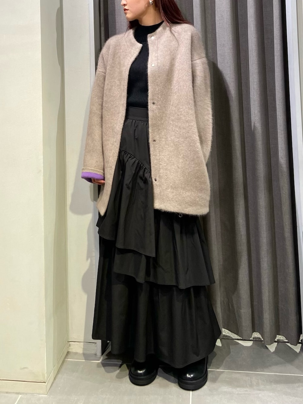 ベージュ系のカーディガン/ボレロ、ブラック系のスカート、ブラック系のブーツを着用したレディースの秋コーディネートの2枚目の写真