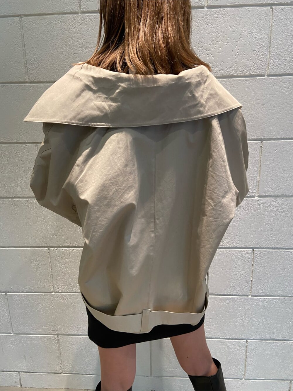 ブラック系のワンピース、ベージュ系のトレンチコート、ブラック系のブーツを着用したレディースの冬コーディネートの4枚目の写真