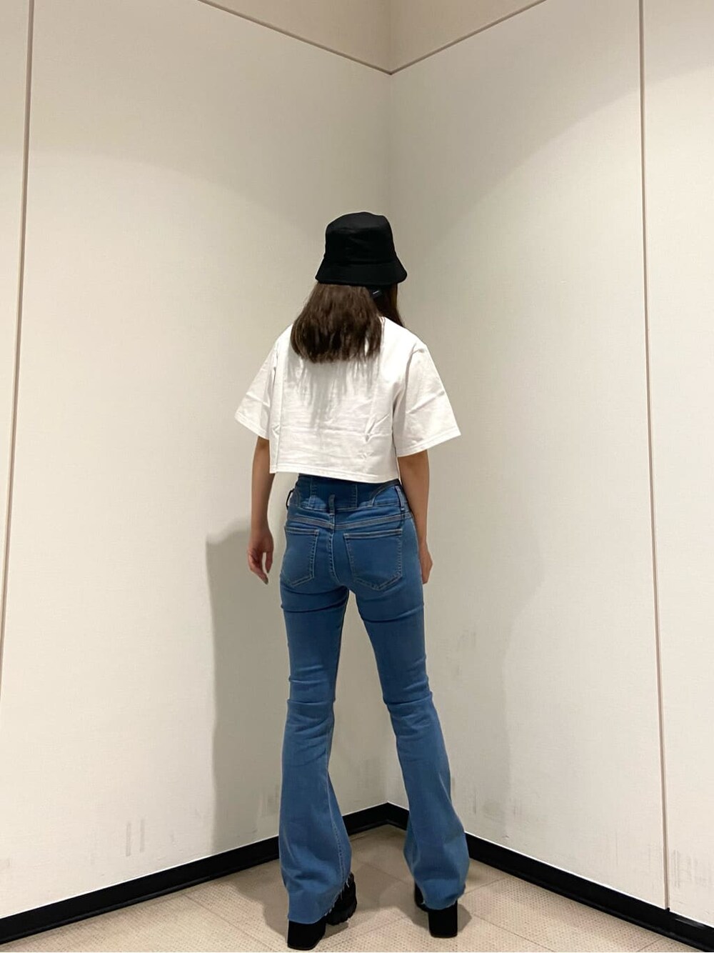 ブルー系のデニムパンツ、ブラック系のサンダル、ホワイト系のTシャツ/カットソーを着用したレディースの夏コーディネートの4枚目の写真