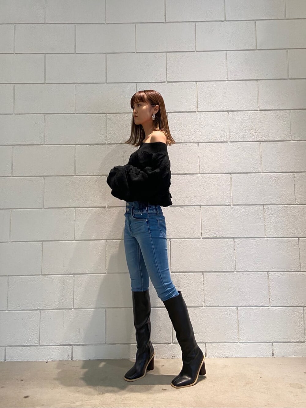 ブルー系のデニムパンツ、ブラック系のブーツ、ブラック系のニット/セーターを着用したレディースの冬コーディネートの2枚目の写真