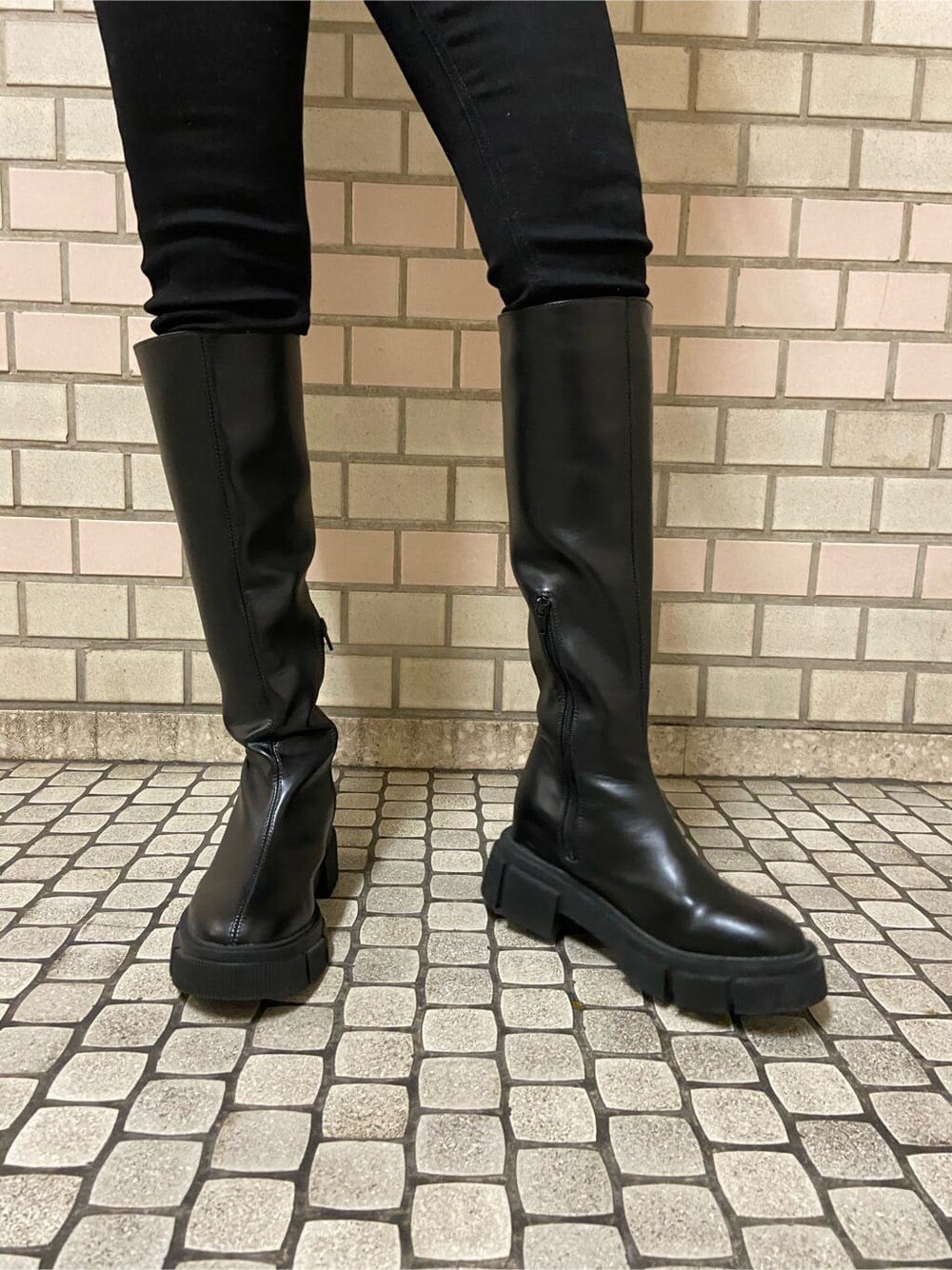 ブラック系のデニムパンツ、ホワイト系のハンドバッグ、ブラック系のブーツを着用したレディースの冬コーディネートの4枚目の写真